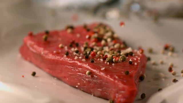 Appetizing piece of raw meat sprinkled with aromatic spices. Very beautiful studio shot. Slow motion. Camera Phantom Flex 4K.
