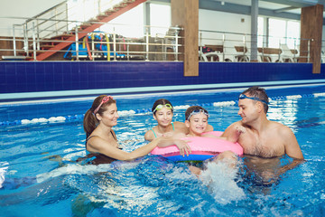 Fototapeta premium A happy family swims in a swimming pool indoors. 