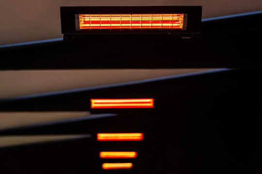 Selective focus and perspective view of many infrared heaters in the ceiling. Abstract construction with orange glow.
