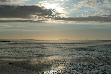 Early sunset on the North Sea directly on the beach. Orange/Blue sky and low tide.