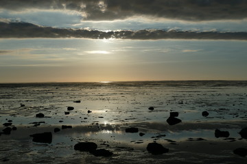 Early sunset on the North Sea directly on the beach. Orange/Blue sky and low tide.