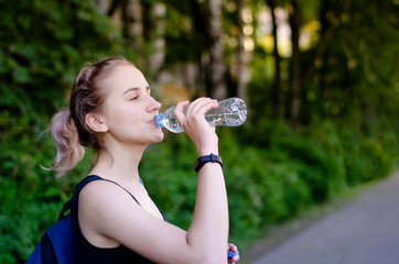 Beautiful girl drinking water after exercise. Playing sport.
