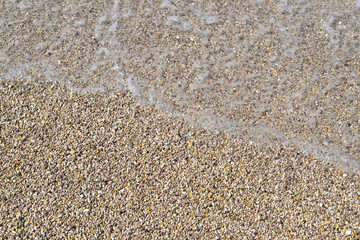 Sea foamy wave on a pebble beach top view