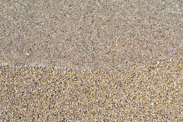Sea foamy wave on a pebble beach top view