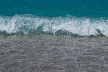 Sea water waves foam lapping to coastal shore