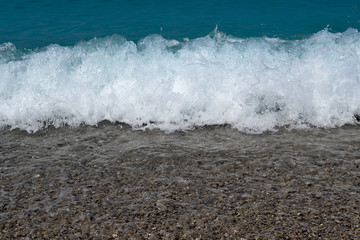 Sea water waves foam lapping to coastal shore