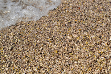 Sea foamy wave on a pebble beach top view