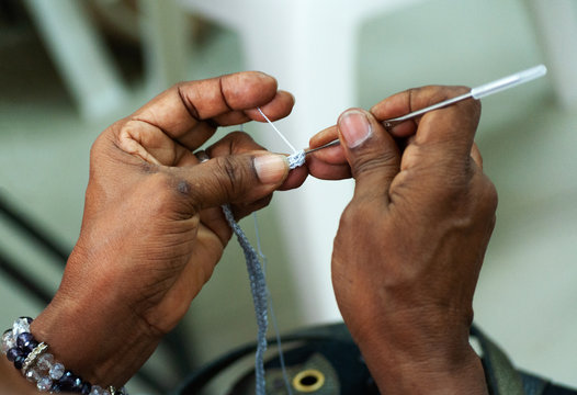 Manos de mujer haciendo crochet con agujas de metal