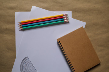 Fototapeta na wymiar White paper ruler, brown note book, multi-colored pencil, educational equipment
