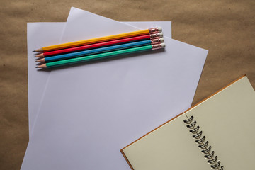 Plakat Multi-colored pencils and brown notebooks on a white background can be used to make backgrounds.