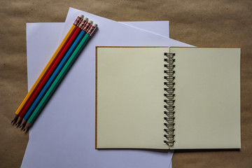 Multi-colored pencils and brown notebooks on a white background can be used to make backgrounds.