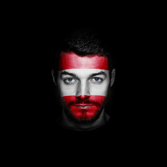 Flag of Austria painted on a face of a man on black background.