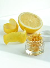 Homemade lip scrub with lemon peel and brown sugar in small glass jar.