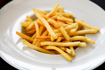 French fries potatoes on a white plate.