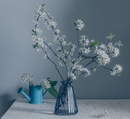 Still life with a bouquet of flowering branches and a watering can. Vintage. Pastel color