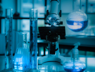 Microscope in microbiology lab for medical research or science development with equipment color liquid chemical liquid to test tubes with lab glassware. in the laboratory concept blue tone.