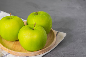 Fresh green apples in dish wooden, with Hand towel on wood table