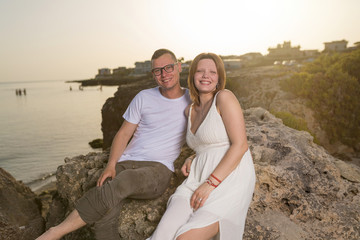 Happy young couple in love smiling by the sea at sunset.