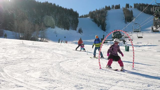 Parents Are Giving Instructions To Their Kids To Ride A Ski In The Resort. Parents are teaching principles of skiing to their kids in ski school. You can see ski lift elevator in this video as well.