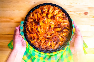 Hands holding homemade delicious apple pie. Close up.