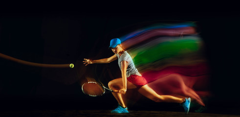 One caucasian woman playing tennis isolated on black background in mixed and stobe light. Fit young...