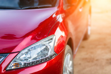 Closeup of headlight of red car outdoors.