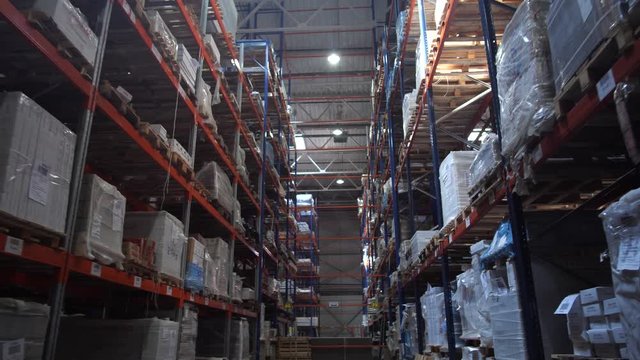 Huge logistic warehouse. Camera movement along high shelves with boxes. 4K Slow Mo