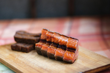 Beer snack. Fried black bread and red smoked fish. Black bread and smoked fish cut into pieces, lie on a wooden Board.