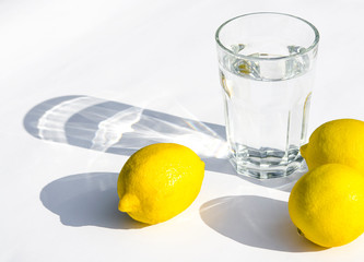 Lemons, fresh green mint and a glass glass with water on a white background. Shadows on a white background