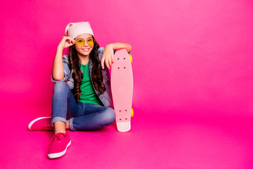 Full length body size photo beautiful little she her curly lady sit floor risky hobby long board hands arms modern look wear yellow sun specs hat casual jeans denim jacket isolated pink background