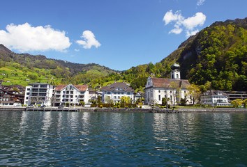 Fototapeta na wymiar Idyllic Swiss village of Gersau, Canton Schwyz, on Lake Lucerne. Beautiful summer day, Buildings reflected in the water.