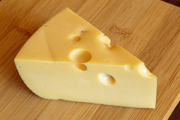 Slicing maasdam cheese on a cutting board.