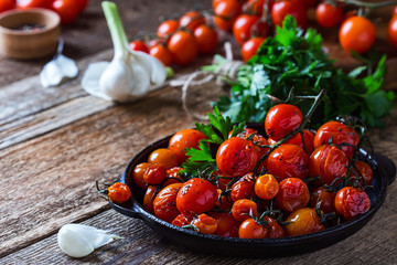 Roasted with herbs cherry tomatoes,  garlic and fresh parsley on rustic  table