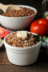 Buckwheat. Porridge with a piece of butter in a glass plate on a brown wooden table. breakfast, healthy food.