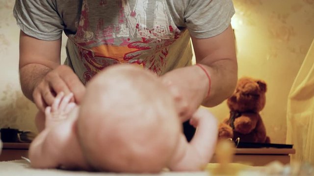 Dad changes the diaper baby. Father changes the diaper to his small child, the action takes place in the nursery. Close-up