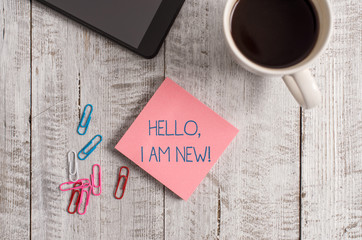Handwriting text writing Hello I Am New. Conceptual photo introducing oneself in a group as fresh worker or student Stationary placed next to a cup of black coffee above the wooden table © Zofia
