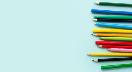 Multicolored pencils on a soft blue background, top view, copy space.