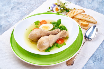 Homemade chicken bouillon with chicken drumsticks on a grunge blue background