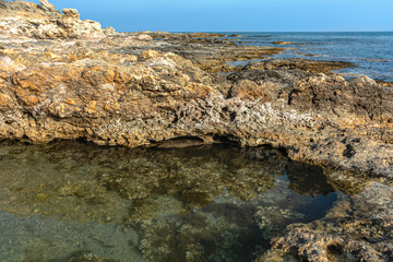 Close-up of Rocky seashore. The stones form a small Bay with clear water. Rhodes. Greece. Colorful background