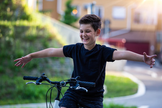 Happy Boy Riding Bike At Sunset. Smiling Child On Bicycle Into The Sun With No Hands