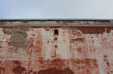the old ruined wall of a brick building with a viewing window crumbled facade