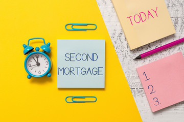 Handwriting text writing Second Mortgage. Conceptual photo lien on property which is subordinate to more senior one Notepads clips colored paper sheet marker alarm clock wooden background