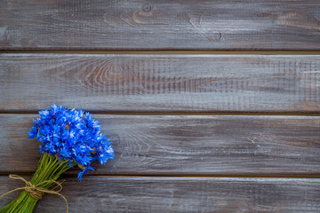 Summer flowers pattern with bouquet of blue cornflowers on wooden background top view mock up