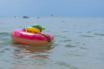 A 3-year-old boy swims in the sea in a life jacket and rubber ring. Persons not visible. Early morning.