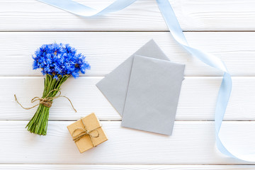 Field flowers design with bouquet of blue cornflowers, box and envelopes for present on white background top view mockup
