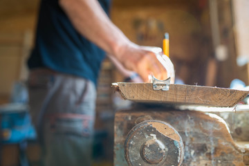 Carpenter marking oak wood board with  yellow pencil in workshop, focus on the board, shallow depth of field, visible dust.