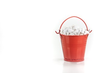 White pills, tablets in red metal bucket on white background.