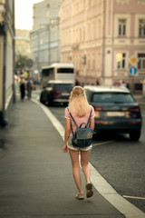 Fototapeta premium Teen girl in shorts and a backpack, is on the highway of Moscow, sunset.