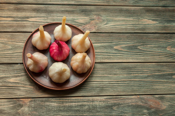 pickled garlic in a clay plate on a wooden table