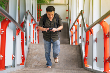 Man walking up stairs and using smartphone in city